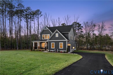 View of front facade featuring a yard, a porch, driveway, and board and batten siding