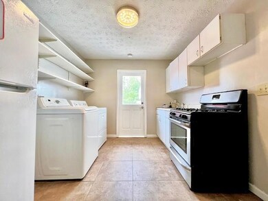 Laundry room with washing machine and clothes dryer, light tile patterned floors, and a textured ceiling