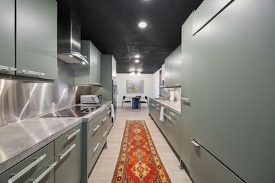 Kitchen with range hood, stainless steel backsplas