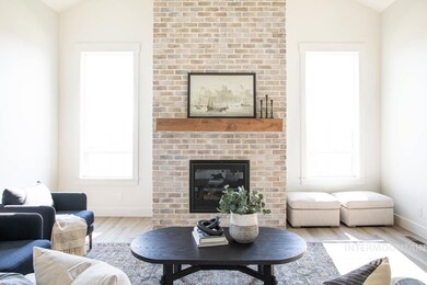 Living room with lofted ceiling, wood finished floors, and a brick fireplace
