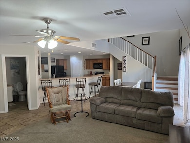 Living room with ceiling fan, stairway, and basebo