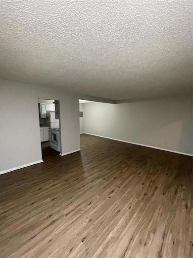 Unfurnished living room featuring dark wood finished floors and a textured ceiling