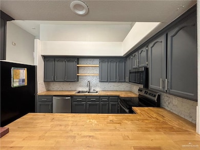 Kitchen featuring a sink, tasteful backsplash, appliances with stainless steel finishes, and butcher block counters