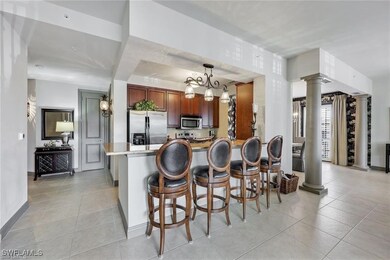 Kitchen with decorative columns, a kitchen breakfast bar, stainless steel appliances, decorative light fixtures, and a peninsula