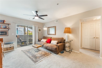 Carpeted living area featuring ceiling fan and bas