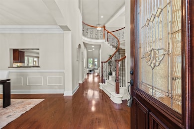 Inviting front entry boasts wood flooring, high ceiling and neutral paint color.