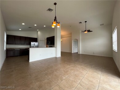 Kitchen featuring open floor plan, hanging light fixtures, dark brown cabinets, arched walkways, and recessed lighting