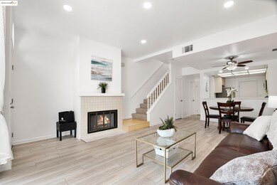 Living area featuring light wood finished floors, recessed lighting, a tiled fireplace, a ceiling fan, and stairs