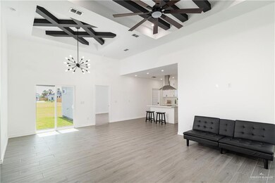 Living area with coffered ceiling, beam ceiling, light wood-style floors, baseboards, and recessed lighting