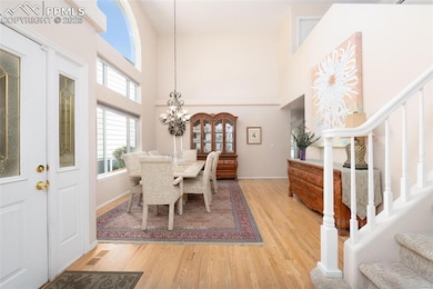 Dining space with stairs, wood finished floors, a high ceiling, a chandelier, and baseboards