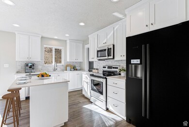 Kitchen with stainless steel appliances, light countertops, tasteful backsplash, wood finished floors, and recessed lighting