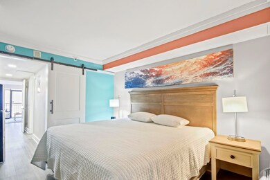 Bedroom featuring visible vents, wood finished floors, a barn door, and baseboards