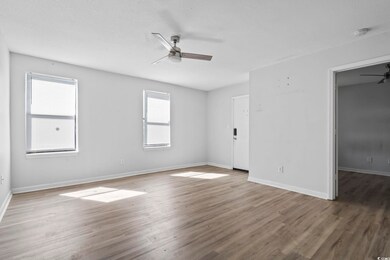 Empty room with a textured ceiling, dark hardwood 