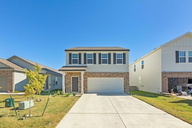 View of front of property with a front lawn, driveway, brick siding, and an attached garage