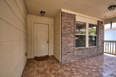 Property entrance with brick siding and covered p