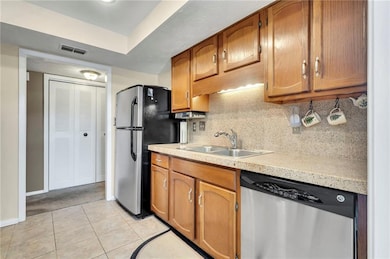 Kitchen featuring backsplash, stainless steel appliances, light colored carpet, and sink