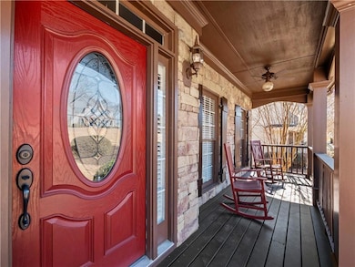 View of exterior entry with stone siding, covered porch, and ceiling fan