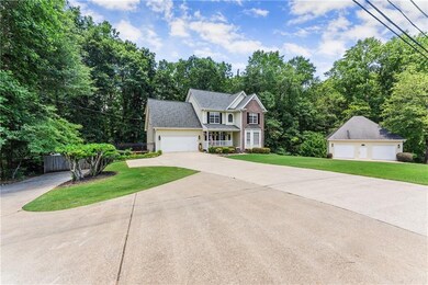 View of front of house featuring a garage, concrete driveway, an outdoor structure, and view of scattered trees