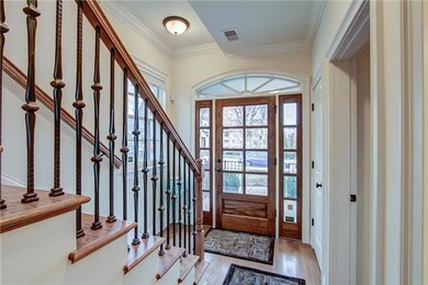 Beautiful entry with glass front door and gleaming hardwood floors, iron balusters.