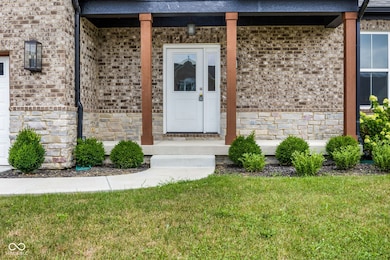 property entrance featuring brick siding, stone siding, roof with shingles, and a lawn
