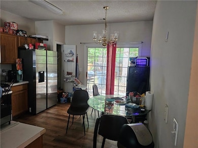 Dining room featuring dark wood-style floors, a chandelier, and a textured ceiling