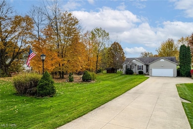 View of front of property with a front yard, driveway, and an attached garage