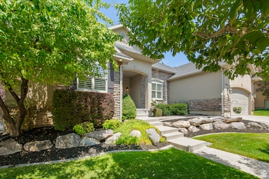 View of front of home with a garage, stone siding, a front lawn, stucco siding, and concrete driveway