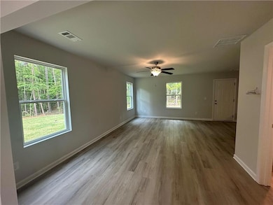 Empty room featuring baseboards, ceiling fan, wood