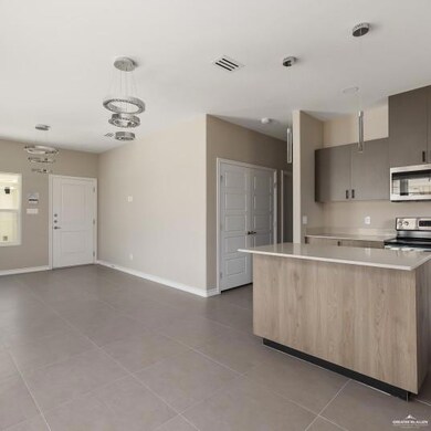 Kitchen featuring hanging light fixtures, light tile patterned floors, modern cabinets, a center island, and light brown cabinetry