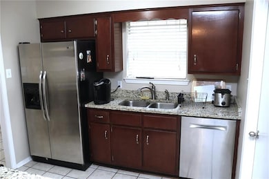 Kitchen featuring Granite countertop with stainless steel Appliance, light tile patterned flooring, and dark brown cabinetry