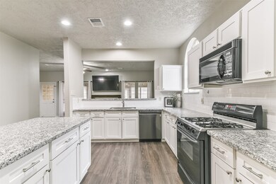A raised breakfast bar allows for additional serving or seating space that extends from the family room into this beautifully updated island kitchen finished with sleek granite countertops, a timeless subway tile backsplash, and white shaker-style cabinetry.