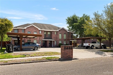 View of front facade with covered and uncovered parking and brick siding
