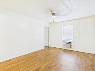 Unfurnished room featuring light wood-style flooring, a textured ceiling, ceiling fan, and a wall unit AC