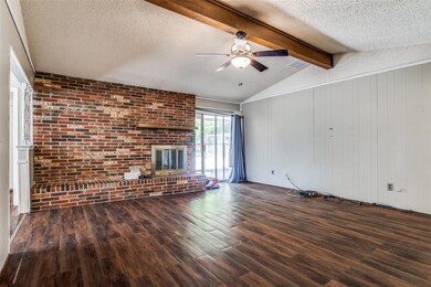 Unfurnished living room with ceiling fan, a brick fireplace, a textured ceiling, brick wall, and dark hardwood / wood-style floors