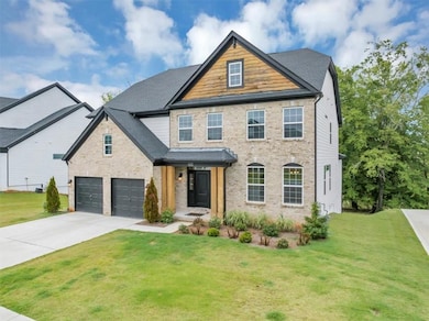 View of front facade featuring brick siding, concrete driveway, a front lawn, and an attached garage