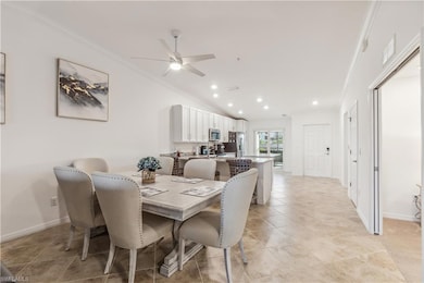 Tiled dining room featuring ceiling fan, lofted ceiling, and ornamental molding