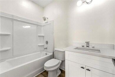 Bathroom featuring washtub / shower combination, vanity, and dark wood-style floors