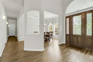 Foyer entrance featuring ornamental molding, Luxury Vinyl Plank floors, and a chandelier