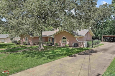 Single story home featuring brick siding, a carport, a front yard, and concrete driveway