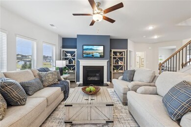 Living area featuring ceiling fan, a fireplace wit