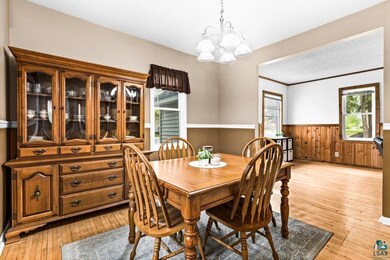Dining area featuring wainscoting, a chandelier, light wood-style flooring, and wooden walls