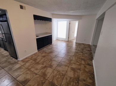 Unfurnished living room featuring light tile patterned flooring and a textured ceiling