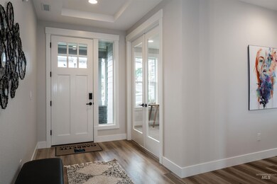 Foyer featuring light wood-style flooring, french doors, a raised ceiling, and recessed lighting