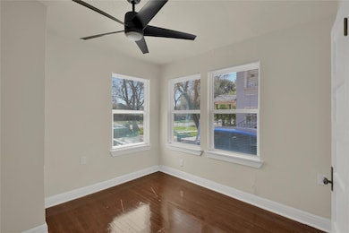Unfurnished room featuring dark wood finished floors, healthy amount of natural light, and a ceiling fan