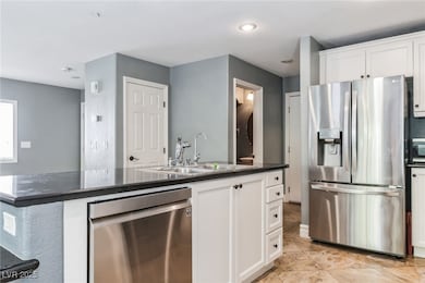 Kitchen featuring stainless steel appliances, white cabinets, and a kitchen island with sink
