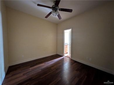 Spare room featuring dark wood finished floors, baseboards, and ceiling fan