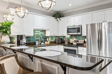 Kitchen featuring pendant lighting, appliances with stainless steel finishes, dark stone counters, and white cabinets