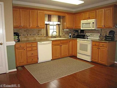 Kitchen. The kitchen offers a lovely tiled backsplash, neutral colors, solid surface counters, matching appliances, and gleaming hardwood floors! With such space, all household chefs can collaborate simultaneously!