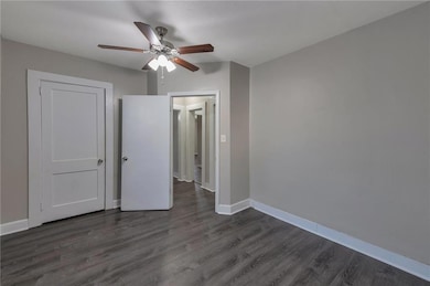 Unfurnished bedroom featuring dark hardwood / wood-style floors and ceiling fan