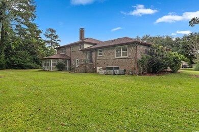 Back of property with a lawn, a sunroom, and centr